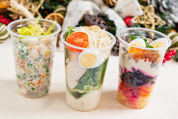 Three clear cups with layered salads showcase fresh veggies, protein, and colorful toppings