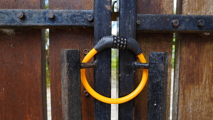 Yellow combination padlock with numeric code attached to a wooden and iron gate, partially blurred. Security concept with selective focus, perfect for background, design, or safety-related themes