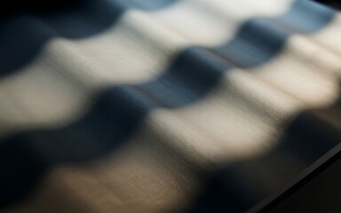 Abstract wavy pattern of light and shadow on a dark textured surface
