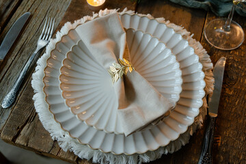 Elegant Christmas crockery. Table setting with white plates, linen napkin and decorative elements. 