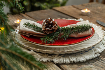 Festive Christmas table decor. Plates and napkin decorated pine cone and spruce twig