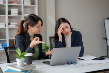 Businesswoman talking with stressed colleague at office desk