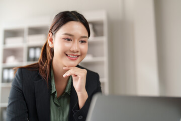 Fototapeta premium Young businesswoman smiling while working on laptop