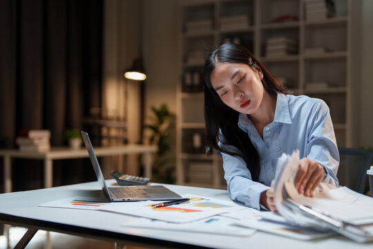 Young asian businesswoman working late managing financial documents