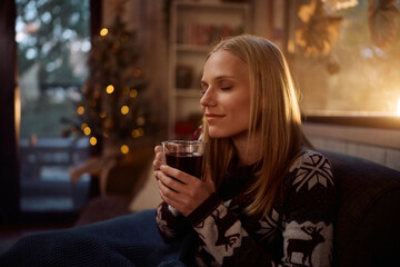 Smiling woman enjoying in mulled wine while spending Christmas at home.
