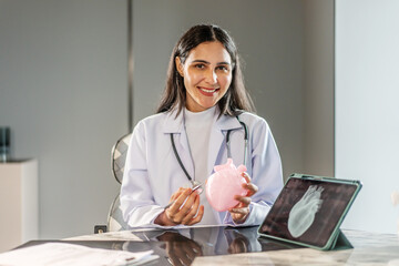 Portrait of a smiling female doctor cardiologist showing model of the heart and looking at the camera in a hospital office or clinical examination room, Healthcare and medical service
