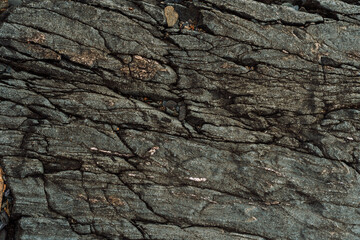 Dark layered rock surface with long intersecting cracks. High quality photo