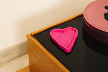 A craft made by a child of a pink heart with the word "mama"