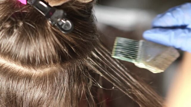 Coloring hair with precision, highlighting strands while using gloves and a brush to create a stunning transformation at a bustling salon