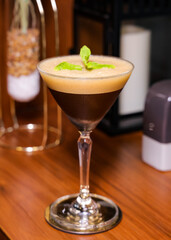 An espresso martini, artfully presented with a mint garnish
