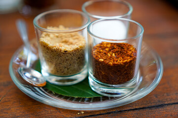 Close up of Thai condiment glasses for noodles with peanut, chili, and seasoning on the table