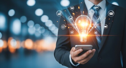 Businessman holding smartphone with glowing light bulb and business icons, concept of innovative ideas and creative solutions