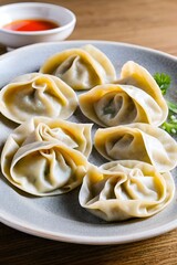 there is a plate of dumplings on a table next to a bowl of dipping sauce