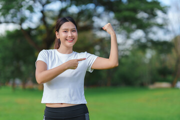 Young woman flexing bicep, pointing, showing fitness