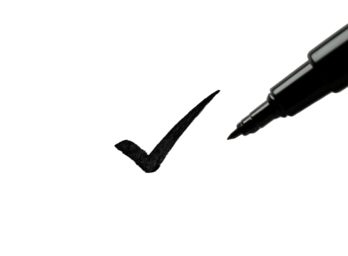 Black marker creating a checkmark on a dark surface