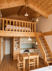A duplex room in wooden interior with two levels and bedroom upstair, kithcen pantry, dining table downstair.