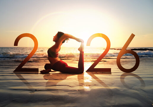 Happy new year card 2026. Silhouette of healthy girl doing Yoga One Legged Pigeon pose on tropical beach with sunrise or sunset sky background, woman practicing yoga as a part of the Number 2026 sign.