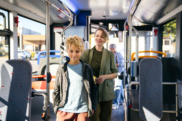 Mother and young son share a bright, happy moment while riding a city bus together during their daily urban commute and journey