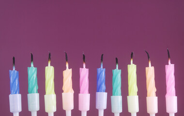 Many colourful birthday cake candles on purple background