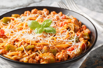 American spaghetti with rich tomato sauce, minced meat, parmesan, green pepper and spices close-up in a plate on the table. Horizontal