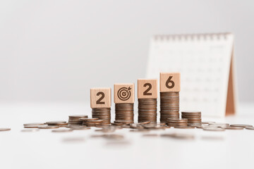 Stacks of coins with Calendar and wooden blocks forming number 2026 for target financial growth, investment planning for money savings, business goals concept. Budget and tax, Happy new year 2026