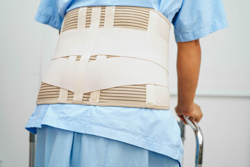 Asian woman wearing lumbar support pain back and use walker in hospital.