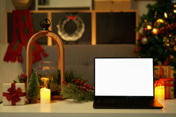 Front view of white screen laptop in home with Christmas tree warm light. Remote work. freelance. Work from home. Telework.