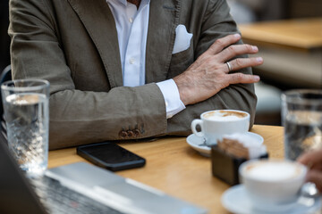 Businessman relaxing at cafe with cappuccino and laptop