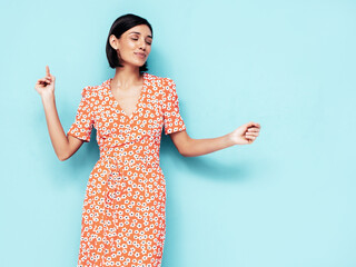 Young beautiful smiling female in trendy summer red dress. Sexy carefree woman posing near blue...