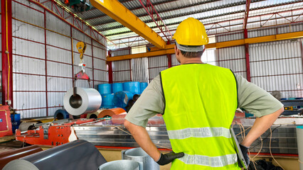 Worker observing machinery operations in industrial warehouse steel production facility workplace environment