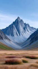 Jagged Mountain Peak Under a Clear Blue Sky With a Foreground of Golden Grasses and Wildflowers in the Alaskan Wilderness