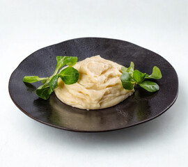 Creamy hummus dip with fresh green garnish on a dark plate