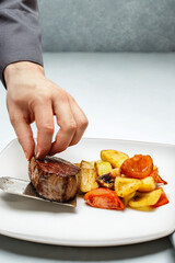 Chef plating a perfectly cooked steak with roasted vegetables