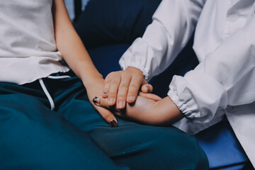 Doctor giving hope. Close up shot of young female physician leaning forward to smiling elderly lady patient holding her hand in palms. Woman caretaker in white coat supporting encouraging old person