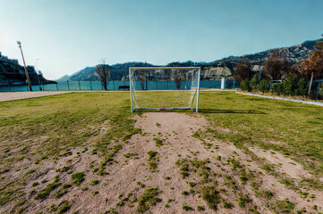 Empty soccer field with goal and mountainous background under clear sky