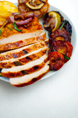 Delicious sliced grilled chicken breast with roasted vegetables and lemon