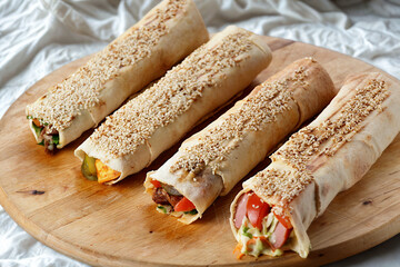 Four deliciously wrapped shawarma sandwiches on a wooden board