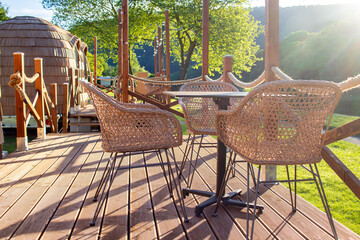 Wooden terrace with tables and chairs in front of igloo-shaped wooden huts at a campsite by a river