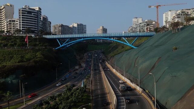 Aerial view tracking forward towards the iconic Puente de la Paz between Miraflores and Barranco districts of Lima, with city traffic below