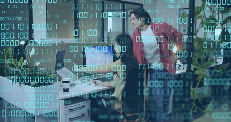 Collaborating colleagues reviewing charts in tech office, with monitors keyboard and binary overlay