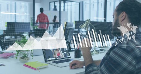 Gesturing male office worker using laptop in open plan office with graphs overlay, copy space