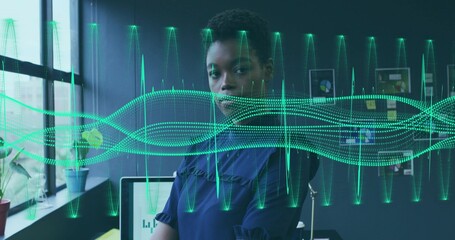 Reviewing charts tech professional woman wearing blue blouse at desk in office, with waveforms