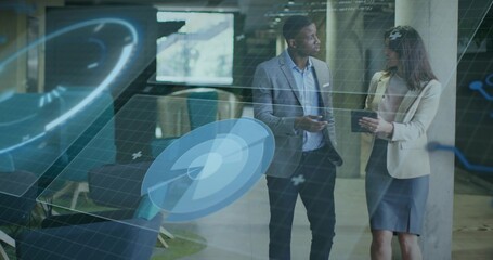 Coworkers analyzing holographic charts holding smartphone and tablet wearing suits in office lounge