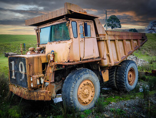 Obraz premium Abandoned 1960s Rusty Dump Truck in Waratah, Tasmania Under an Ominous Sunset Sky