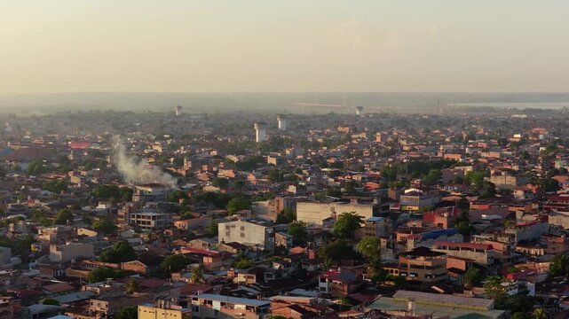 Panoramic aerial view of Peruvian city of Iquitos during a warm, hazy sunset, showing urban landscape and Amazon River