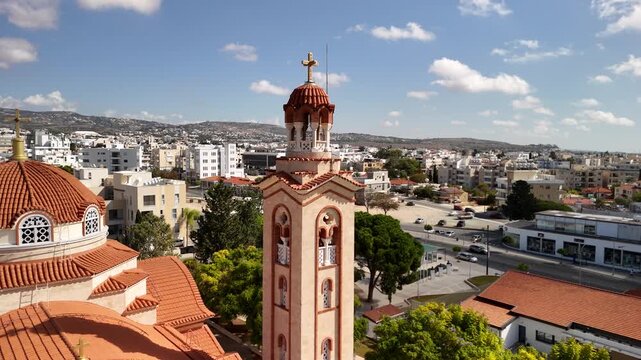 A beautiful perspective of a church tower in Pathos, Cyprus, showcasing the vibrant town below. The bright sky enhances the charm of the surrounding area.