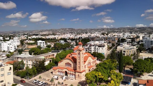 View the captivating skyline of Paphos, Cyprus, featuring the impressive Agios Nikolaos Church. Discover the charm of this city with green spaces and white buildings.