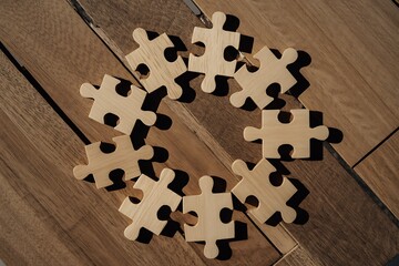 Light wooden jigsaw pieces form a creative circle on a rustic wooden background, perfect for teamwork, problem solving, and achieving goals