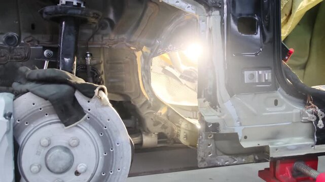 Broken car without tire and glowing lamp in repair workshop closeup. Maintaining automobile on hydraulic lift platform at service station