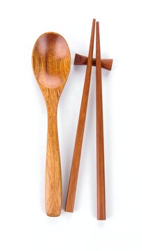 Wooden spoon, chopsticks, and chopstick rest on white